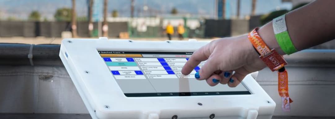 Hand tapping a point-of-sale terminal at an outdoor event
